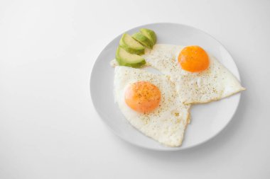 Avokado ile çırpılmış yumurta ve beyaz arka planda beyaz bir tabakta, boş fotokopi alanı, üst görünüm