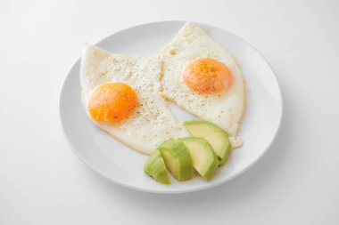 Avokado ile çırpılmış yumurta ve özellikle beyaz arka planda beyaz bir tabakta. Yakın çekim, üst görünüm