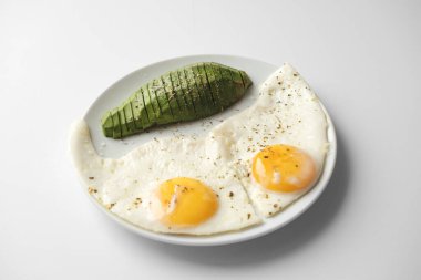 Avokado ile çırpılmış yumurta ve özellikle beyaz arka planda beyaz bir tabakta. Yakın çekim, üst görünüm