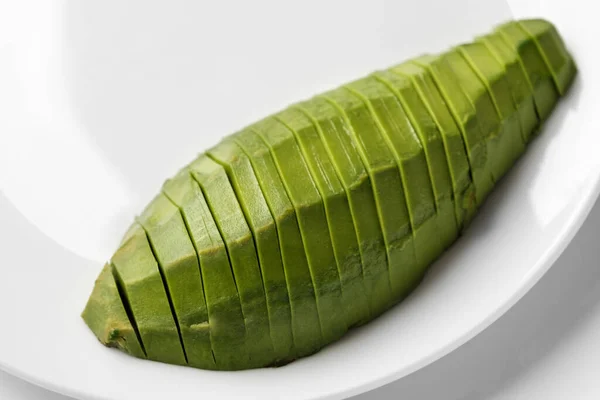 Sliced half avocado on a plate on white background with copy space. Close-up, top view — Stock Photo, Image