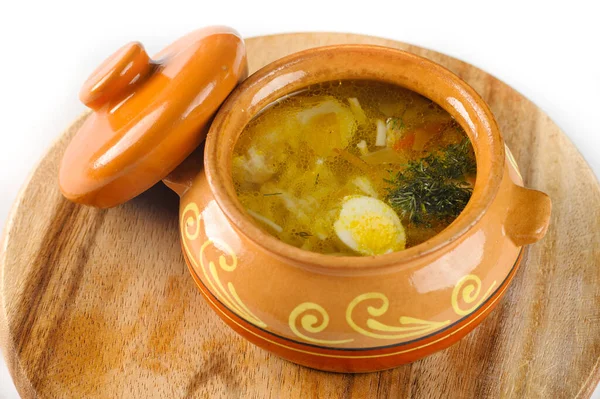 Noodle soup with chicken and quail egg in a pot on round wooden Board view closeup — Stock Photo, Image