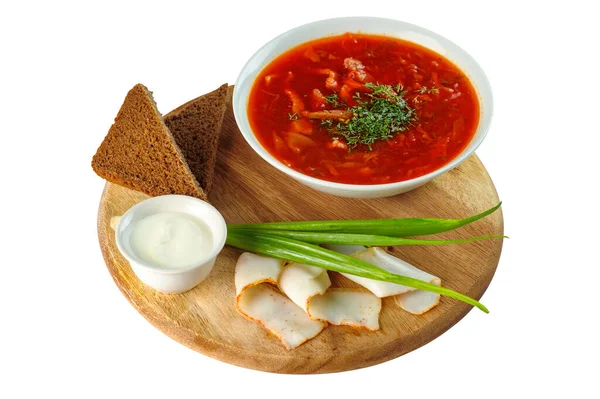 Borscht with sour cream, green onions, bacon and rye bread on a round wooden Board on white background — Stock Photo, Image