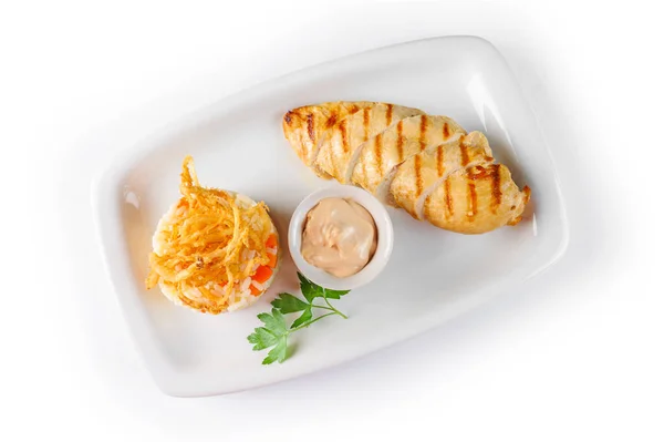 Gebackene Hühnerbrust mit Sauce und Reis mit Gemüse auf weißem rechteckigen Teller auf weißem Hintergrund, Draufsicht Stockbild
