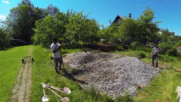 Equipo de trabajadores lanza grava con palas en la construcción. 4K . — Vídeos de Stock