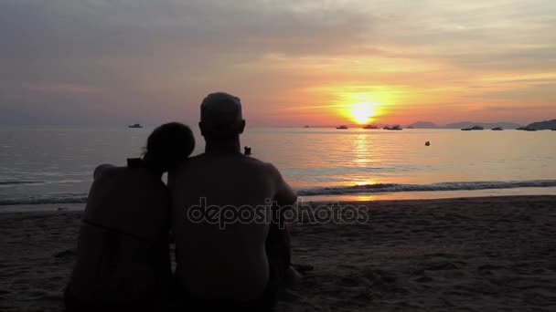 Par siddende på stranden ved solnedgang – Stock-video