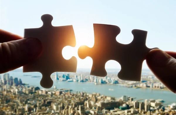 Putting puzzle pieces together on sky background with sunlight — Stock Photo, Image