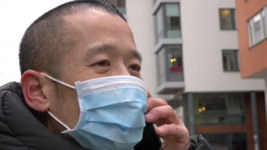 Orta yaşlı Asyalı adam tıbbi maske takıyor.