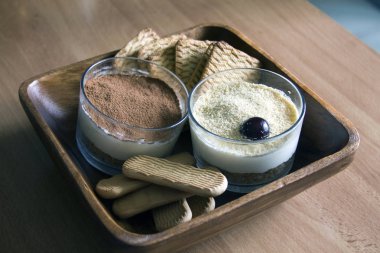 Süt cheesecake, kiraz, gözlük kurabiye erken yaz sabahları bulanık bir arka plan üzerinde ahşap bir masa üzerinde bir ahşap kase ile süslenmiş