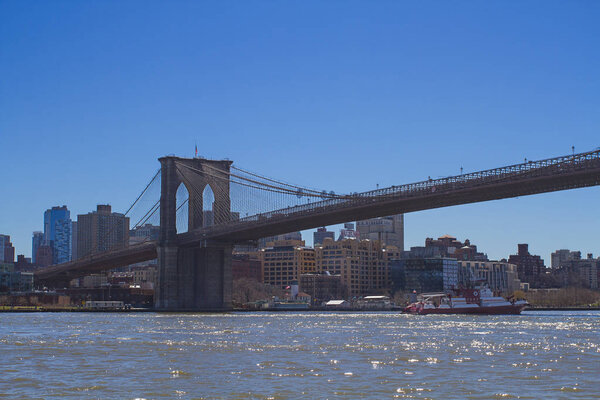 Lanscape view of the Brooklyn Bridge with FDNY boat passing by