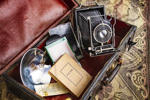 vintage case of camera equipment containing medium format camera, film boxe, flash, and notes