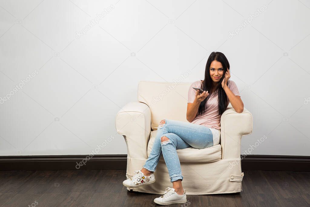 young woman sitting on a white couch, talking on her phone