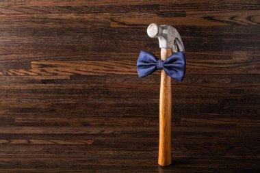 Koyu renk ahşap arka planda mavi papyonlu eski püskü bir çekiç.