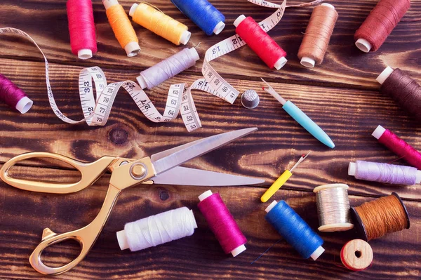 sewing tools and multi-coloured threads on a wooden background