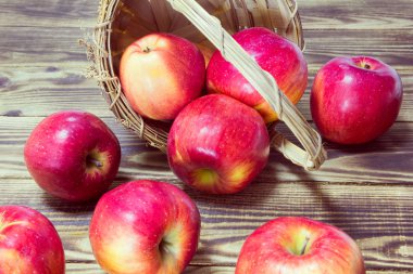 Kırmızı elma bir sepeti ahşap bir arka plan üzerinde silindir dışarı