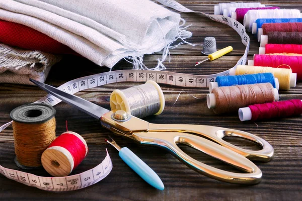 Sewing tools, multi-coloured fabric and threads on a wooden background — Stock Photo, Image