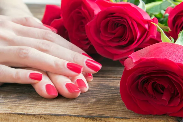 Red nail manicure with red roses around — Stock Photo, Image