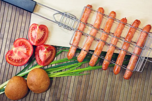 Grelha para salsichas e tomate, pão, cebola — Fotografia de Stock