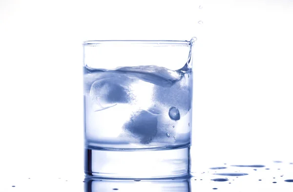 Blue water splashing out of a glass with drops — Stock Photo, Image