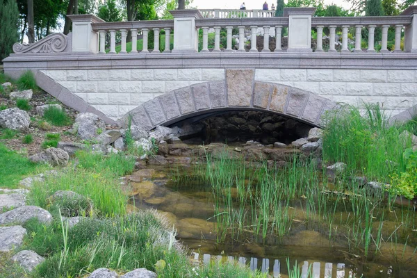 Marble bridge over a lake in a green garden — Stock Photo, Image