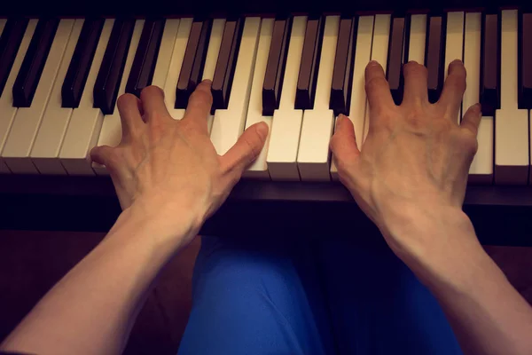 Manos de las mujeres tocando el piano sobre un fondo oscuro — Foto de Stock