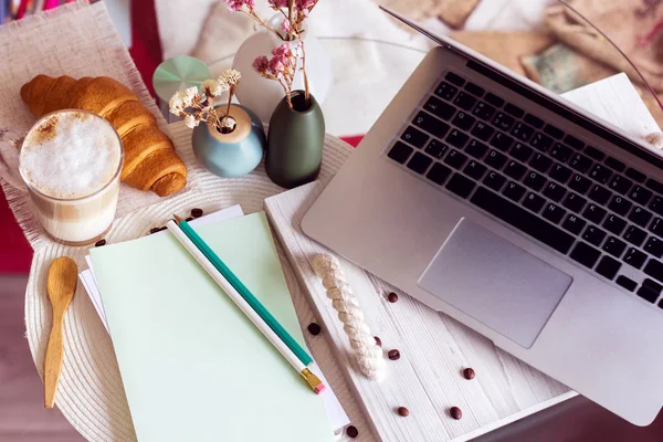 Skrivbord med laptop, kaffe och croissant — Stockfoto