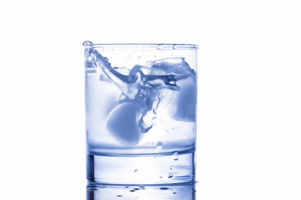 Água azul salpicando de um copo com gotas — Fotografia de Stock