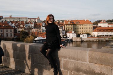 Çek Cumhuriyeti Prag 'da Charles Köprüsü' nde siyah kazak giyen mutlu kızıl saçlı turist.