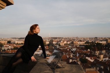 Mutlu kızıl saçlı kadın Prag merkezine ve Charles Köprüsü manzarasına yukarıdan bakarak yeni bir hayata başlıyor.