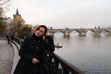Redhead woman from her back and Charles Bridge view in early morning in Prague, Czech Republic - Fog and mist