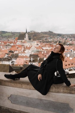 Cesky Krumlov 'da şehir merkezi, kale ve St. Vitus Kilisesi' nin çatı manzaralı kızıl saçlı mutlu bir kadın.