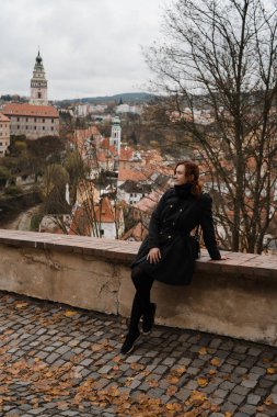 Cesky Krumlov 'da şehir merkezi, kale ve St. Vitus Kilisesi' nin çatı manzaralı kızıl saçlı mutlu bir kadın.