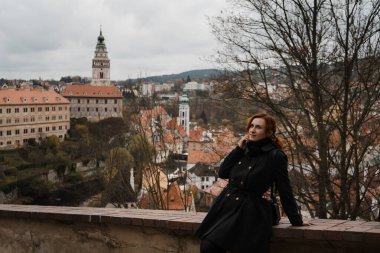 Cesky Krumlov 'da şehir merkezi, kale ve St. Vitus Kilisesi' nin çatı manzaralı kızıl saçlı mutlu bir kadın.