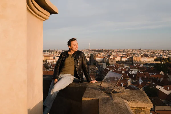 Happy man start fresh new life looking at Prague centre and Charles Bridge view from above and using phone to take a selfie photo