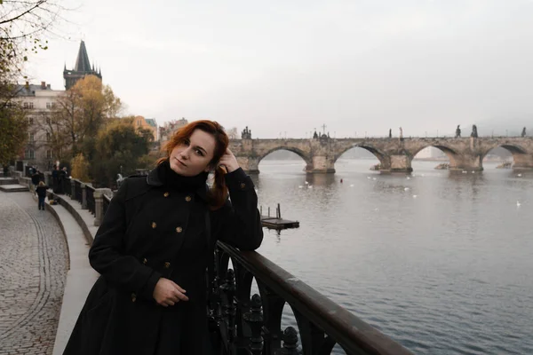 Redhead woman from her back and Charles Bridge view in early morning in Prague, Czech Republic - Fog and mist