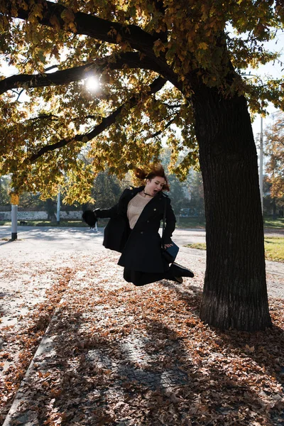 Glückliche rothaarige Frau, die mit Herbstblättern wirft und spielt und ein neues Leben in Prag beginnt — Stockfoto