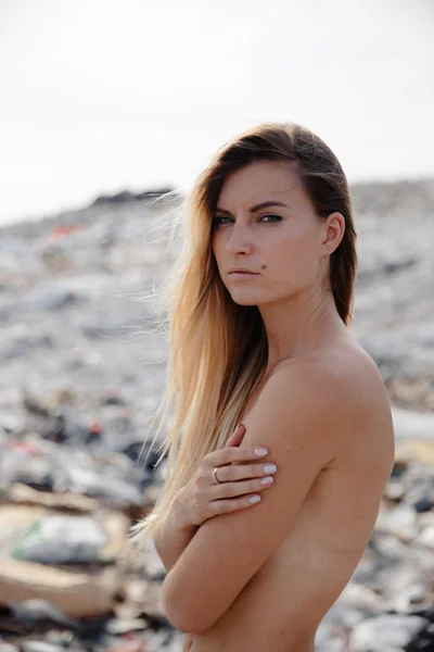 Naturförorenande aktivist på en enorm soptipp utomhus - naken topless blond kvinna - Tittar på allt mänskligt avfall och plast i vår värld - Fiskmåsar flyger i Östeuropa Lettland Riga — Stockfoto