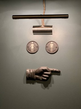 Gri duvarda sağ elini gösteren bir tabela ve Doğu Avrupa 'da Letonya Riga Bar Restoranı' nda ışık saçan bir lamba var.