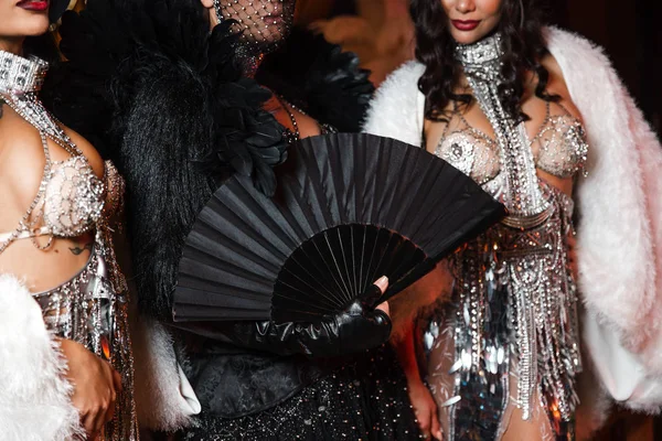 Filles spectacle brillant avec fou en cuir noir et blanc et des tenues de plumes avec des cristaux en Europe de l'Est Lettonie Riga événement d'entreprise tenant ventilateur — Photo