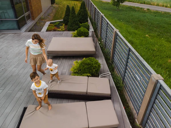Luchtfoto drone: Jonge moeder speelt en heeft plezier met haar zoontje broertjes in een groene tuin met auto 's - Familie waarden warme kleur zomer scene - Oost Europa Letland Riga — Stockfoto