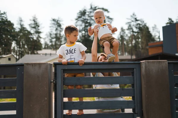 Jovem mãe brincando e se divertindo com seu bebê menino irmãos em um jardim verde com carros - Valores familiares cor quente cena de verão - Leste Europeu Letónia Riga — Fotografia de Stock