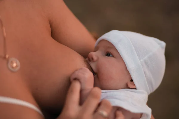 Emzirme: Genç anne parlak kırmızı elbise giyen açık havada onun bebek erkek çocuk emzirir - Oğlu beyaz şapka giyer - Aile değerleri sıcak renk yaz sahnesi el