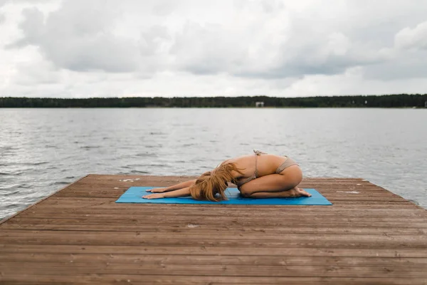 Bulutlu gölde mini bikinili yoga egzersizleri yapan sıska bir kadın - Yoga meditasyonu ve sağlık yaşam tarzı kavramı - Avrupa Doğu Letonya Riga — Stok fotoğraf