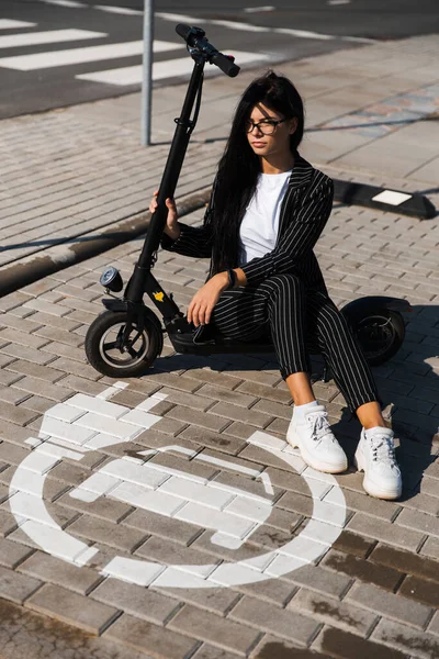 Affärskvinna sitter på elektrisk skoter bär kostym på parkeringen - Utsläppsfri miljövänlig transport — Stockfoto