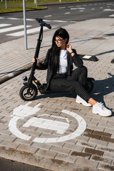 Otoparkta elektrikli scooter 'ın üzerinde oturan iş kadını, ücretsiz eko-dost ulaşımı. — Stok fotoğraf