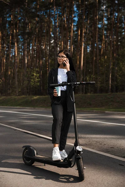 Zakelijke vrouw paardrijden elektrische scooter op parkeerplaats - Emissie gratis eco-vriendelijk vervoer — Stockfoto