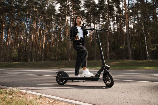 Zakelijke vrouw paardrijden elektrische scooter op parkeerplaats - Emissie gratis eco-vriendelijk vervoer — Stockfoto