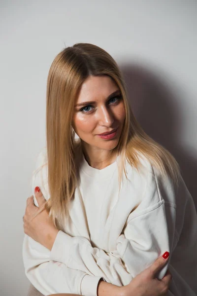 Hermosa mujer glamour pelo largo posando para fotógrafo de cámara con suéter blanco en el cuerpo desnudo - Retrato en una pared de estudio de fondo sin costuras grises — Foto de Stock