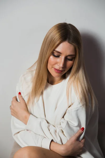 Hermosa mujer glamour pelo largo posando para fotógrafo de cámara con suéter blanco en el cuerpo desnudo - Retrato en una pared de estudio de fondo sin costuras grises — Foto de Stock