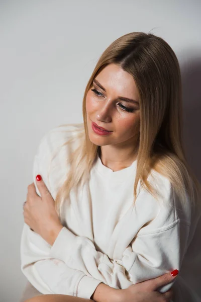 Hermosa mujer glamour pelo largo posando para fotógrafo de cámara con suéter blanco en el cuerpo desnudo - Retrato en una pared de estudio de fondo sin costuras grises — Foto de Stock