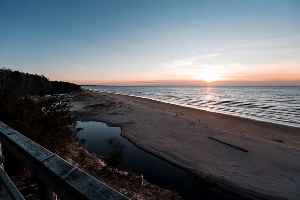 Tramonto a Saulkrasti duna bianca. Vista dal sentiero di legno sul mare, piccolo fiume e cielo — Foto Stock